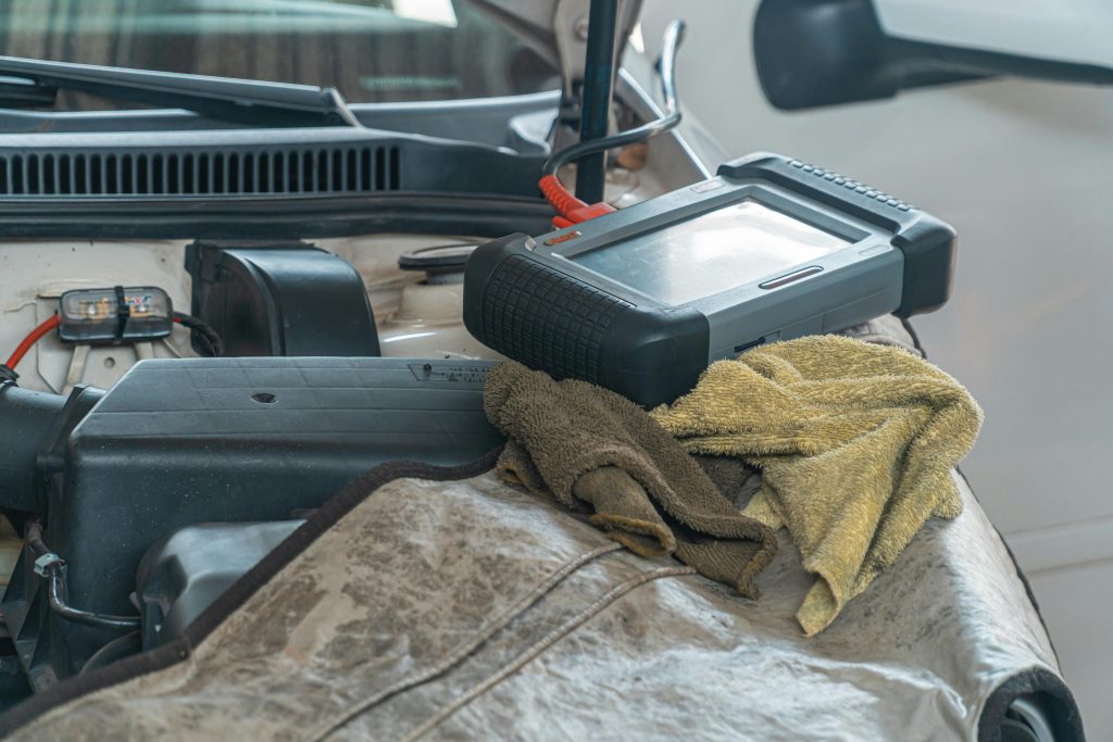 Close-up of car diagnostics tool on engine in a garage setting.